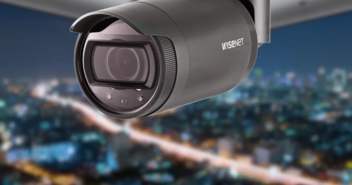 Wisenet Cameras: Night Vision Setup (Wisenet security camera mounted outdoors at night, overlooking a city skyline) | Esentia Systems